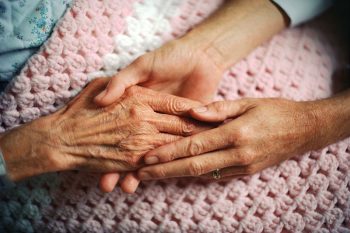 Carpenter Hospice volunteer holding the hand of a palliative care resident